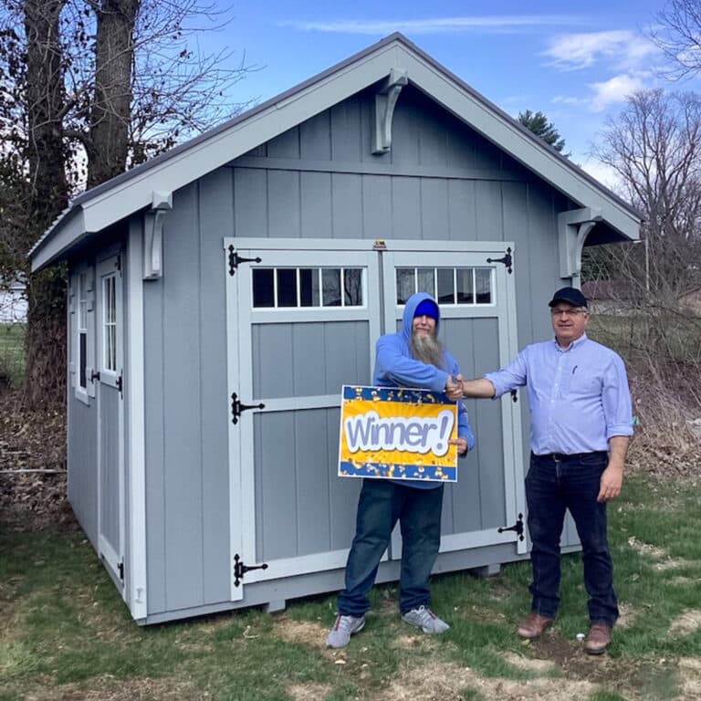 Gray Shed with two men standing in front.